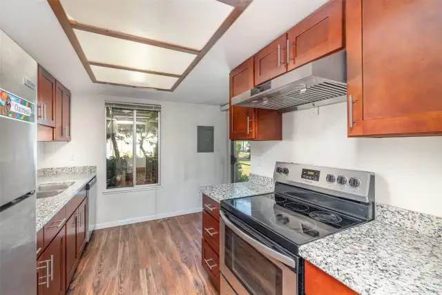 The kitchen boasts warm-toned cabinetry, granite countertops, and stainless steel appliances.