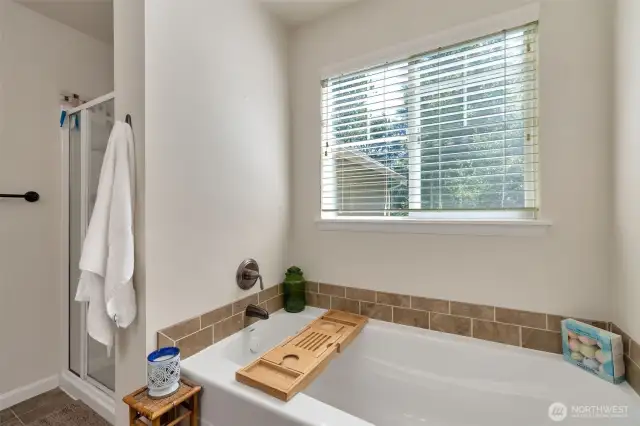 Soaking tub and separate showing in the primary bathroom