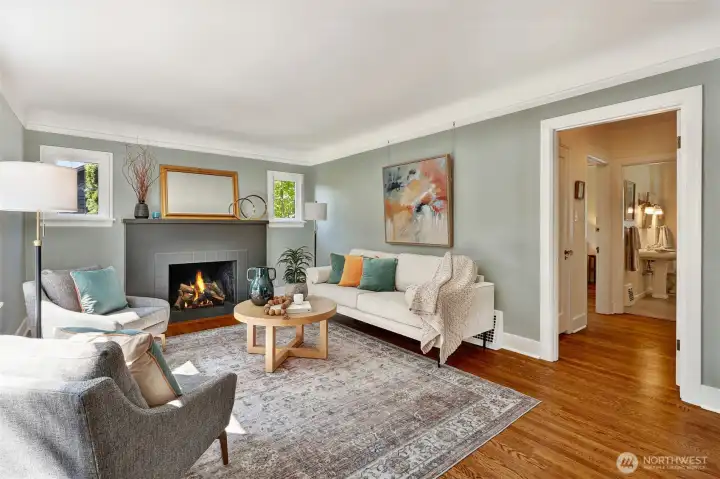 Living room with refinished hardwood floors and wood burning fireplace. Notice all the light!