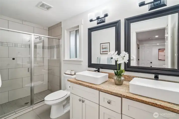 Stylishly appointed primary bathroom boasts dual vanities/sinks and a sleek glass shower.