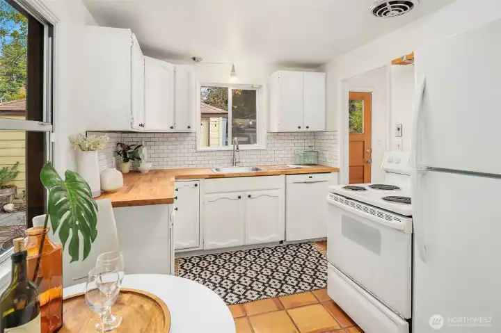 Efficient kitchen with new tile backsplash and  counters and sink.