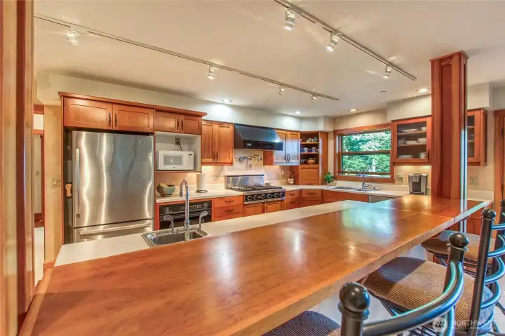 The Bonnie Ward-designed kitchen includes generous wood counter seating for three. Shaker-style natural cherry cabinets and off-white solid surface counters are a stylish today as when they were installed. The Bonnie Ward-designed kitchen includes generous wood counter seating for three. Shaker-style natural cherry cabinets and off-white solid surface counters are a stylish today as when they were installed.