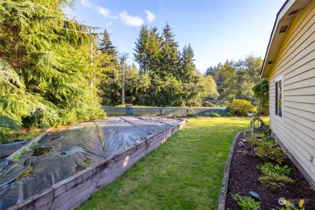 A nice flat yard with raised beds and mature landscape.