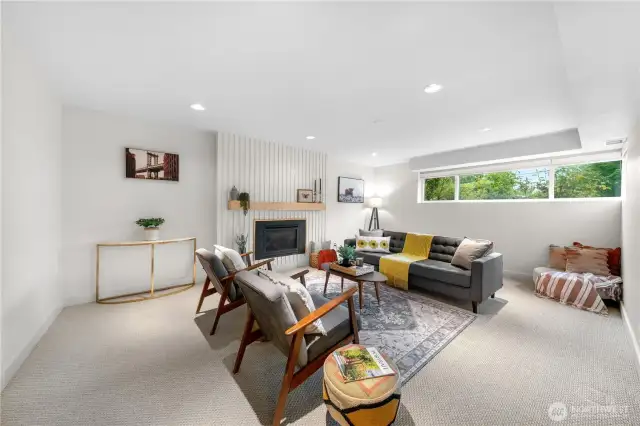Light & bright lower level family room with gorgeous centerpiece gas fireplace surround.