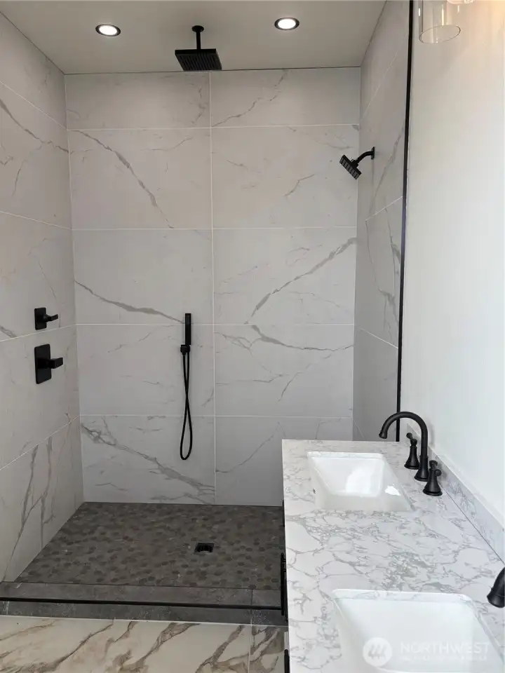 The shower not only has a rainfall shower head on the wall but also has a large shower head on the top of the shower as wll as a handheld shower.
