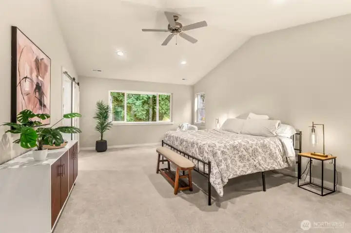 A different angle of the primary bedroom with the view of the lush forest just outside.