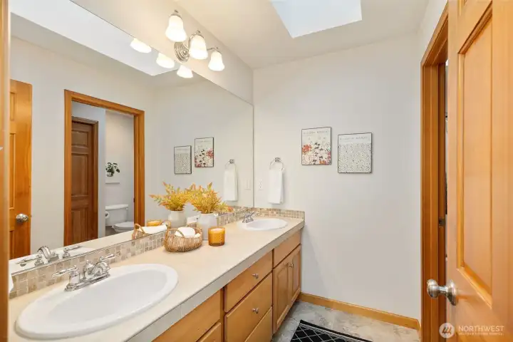 Upstairs full bathroom with dual sink vanity and natural light pouring in through the skylights.