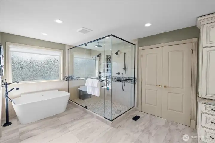 Glass enclosed shower features a rain head & dual fixures complemented by the freestanding tub.