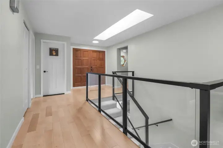 Hardwood floors, a custom metal and glass stairwell system, and a large skylight welcome you.