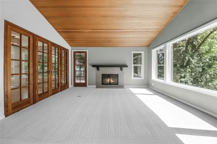 The set of beautiful wood-framed doors lead to the office/library; the door to the left of the fireplace provides convenient access to the deck. A wall of windows floods the room with light.