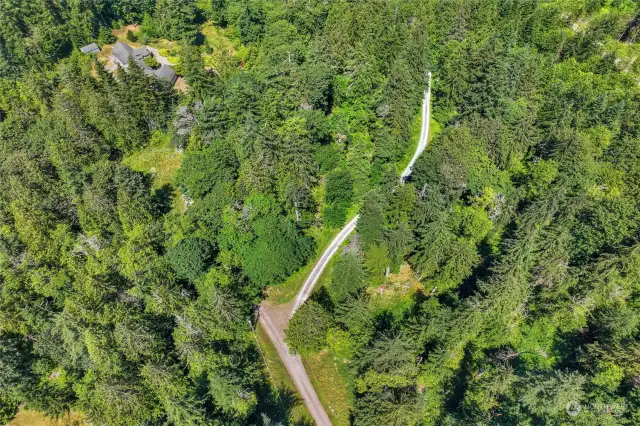 Road split is at the property. Main road sweeps right and the easement for neighbors goes across the flats / saddle.