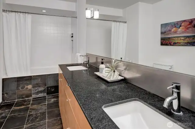 The spa-inspired bathroom features a large counter with two sinks, a deep soaking tub, and a stackable washer and dryer.