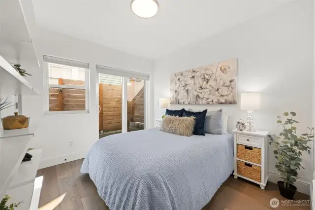 Lower Level Bedroom, with beautiful engineered hardwood flooring, private patio for relaxing with a cup of tea and enjoying nature, built in shelving, spacious room (queen size bed pictured) and large closet