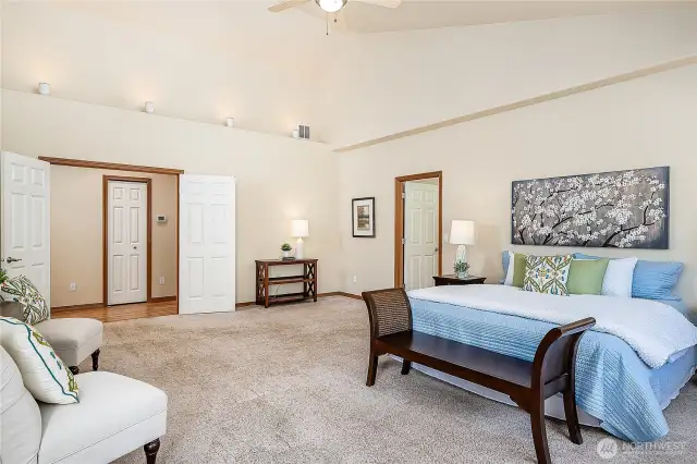 Large French doors welcome you to the Primary Bedroom. This view looks towards the hall (L) and Bathroom (R).