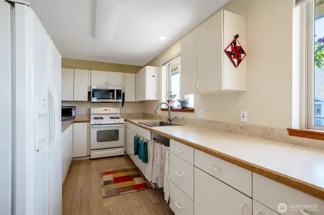 Galley kitchen with laminate flooring and propane stove.