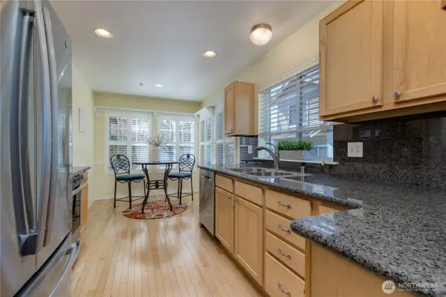 Spacious kitchen with hardwood flooring, granite tile counter & backsplash