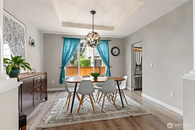 Elegant and inviting dining room defined by stately columns and a tray ceiling with a modern light fixture—ideal for entertaining.