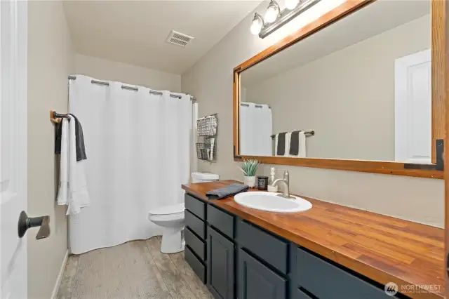 A full bath featuring a wood countertop, a modern sink, and a shower/tub combination.