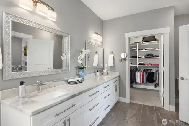 Double sinks, stone counter & walk - in closet beyond.