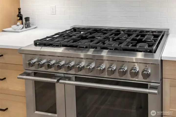 8 burner gas Fisher Paykel range with double oven and stainless steel Zephyr hood.