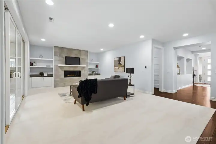 Comfortable and inviting living room with new carpeting, a warm fireplace, and built-ins for stylish storage and display.