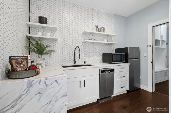 Stylish in-apartment kitchenette offering slab countertops and essential appliances including dishwasher, microwave, and refrigerator.