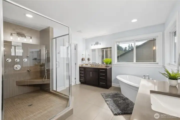Relaxing spa-like primary bath offering a split vanity, soaking tub, and generous custom walk-in tile shower.