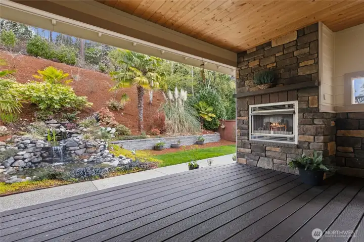 Covered outdoor deck designed for elevated living, complete with a fireplace that enhances ambiance and creates an inviting space for gathering, dining, and relaxing in any season.