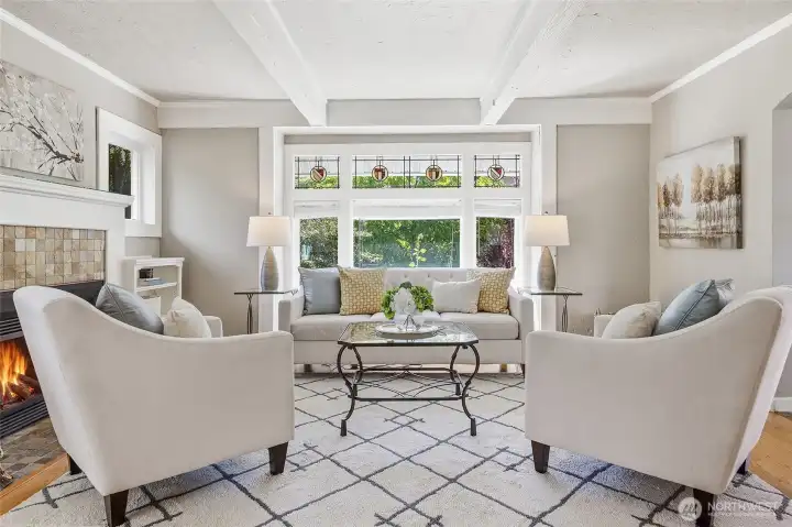 Charming living room with cozy fireplace, beams, stained-glass and leaded windows (other windows are new), crown molding and detailed trim work.