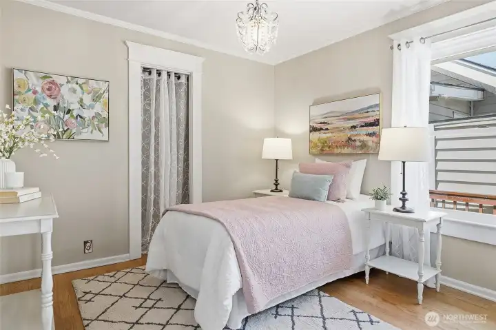 Bedroom 2 on main level with crown molding, gleaming floors, detailed trim and another chandelier!