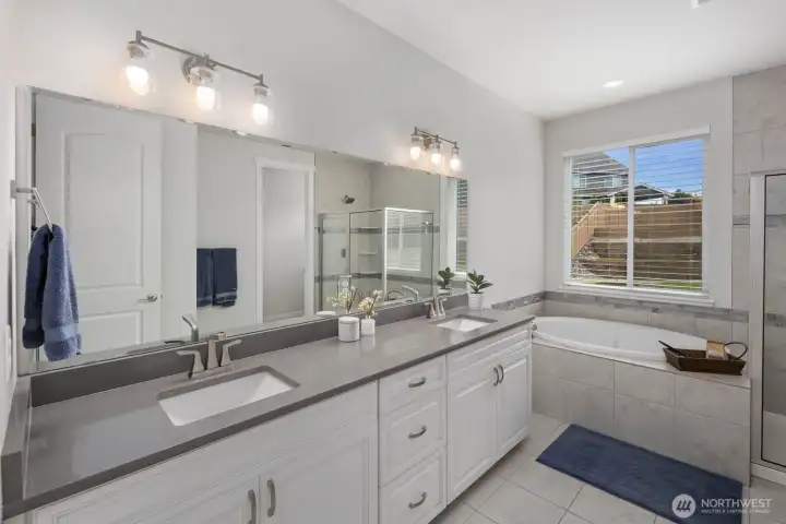 The primary bathroom blends comfort and functionality with dual sinks, abundant counter space, a soaking tub, and a separate shower.