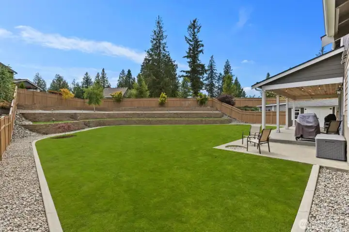 Expansive lawn space and terraced landscaping create a backyard that feels open, private, and ready for everything from play to gatherings.