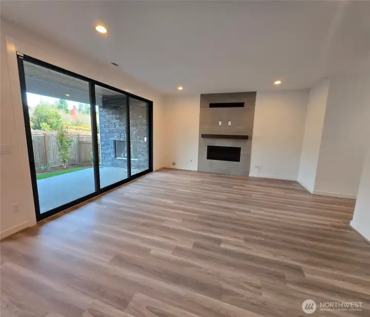 Open great room with sliding stacking doors to outdoor covered patio with gas fireplace