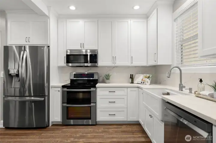 The bright kitchen with apron sink and stainless suite looks so sharp.