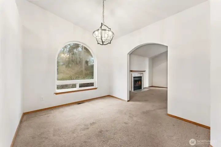 From the kitchen doorway you get a full view of this room and how flexible it really is. The large arched picture window brings in great light, the vaulted ceiling adds height, and the chandelier gives it a finished focal point. The arched opening back to the living room keeps everything connected. It works beautifully as a dining room, but it could just as easily become a library wall, a music space with a piano, or a quieter sitting room depending on what fits your life.