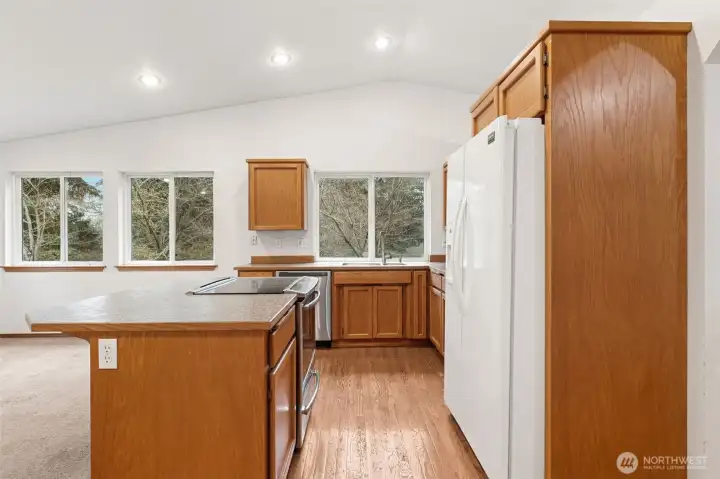 Walking into the kitchen you immediately notice how open it feels. The vaulted ceiling and recessed lighting keep everything bright, and the new stainless glass top range sits right on the island where it’s easy to cook and stay part of the room. Three windows bring in light from both the sink and the family room beyond, and the hardwood flooring carries you right into the space before transitioning to carpet in the living area. The Formica counters are practical in the best way, durable, easy to maintain, and forgiving with everyday use, so you spend less time worrying and more time living.