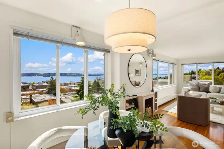 Dining area bathed in natural light with front-row views of Elliott Bay and the Olympic Mountains from the top floor of Hadley House. The open connection to the kitchen makes this space ideal for entertaining. New pendant light fixture adds a modern touch.