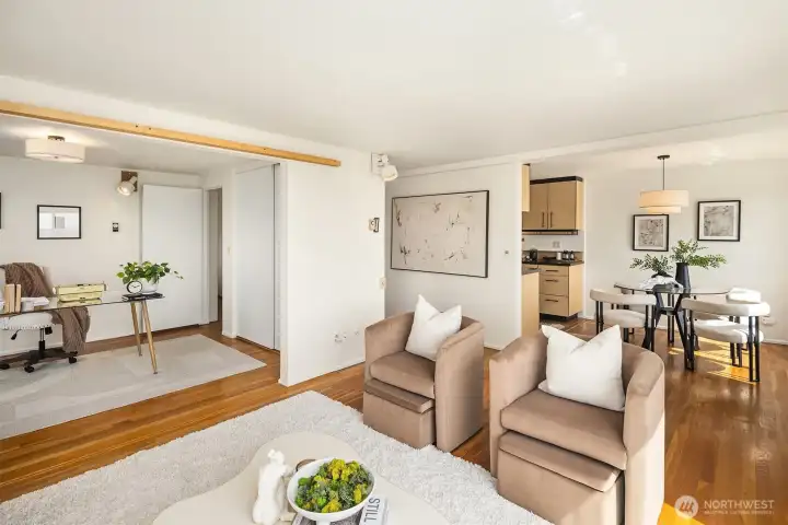 Looking back through the open-plan living space — the 2nd bedroom open as an office/den on the left, the living area in the center, and the kitchen and dining area to the right. The entire floor plan is visible here and shows how well the ~900 sq ft is laid out on the 6th floor of this well-managed co-op.