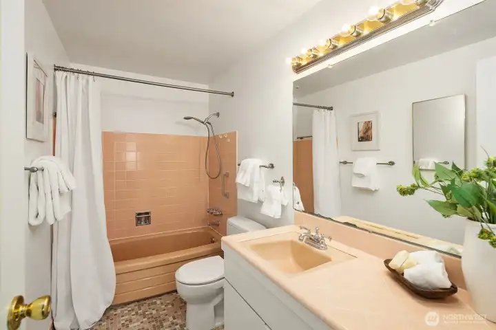 Full bath with original mid-century tile — charming retro character with room to update to your taste. Features tub/shower combo, large vanity with generous counter space, and mosaic tile flooring.