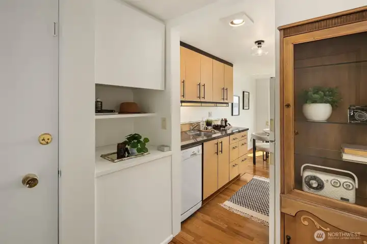 Entry view into the updated kitchen, showcasing the open layout and easy flow between the front entry and the heart of the home. Built-in shelving nook adds display and storage right at the door — a clever use of space you don't often find.