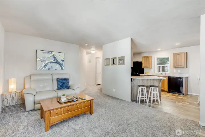 Step into the spacious living room, where plush carpeting and abundant natural light create a warm and inviting space. The open concept floor plan creates a seamless flow between the kitchen, dining, and living areas, perfect for modern living.