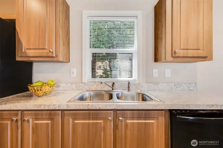 The kitchen boasts a sleek stainless steel sink and beautiful laminate countertops, combining style and functionality for an ideal prep space.