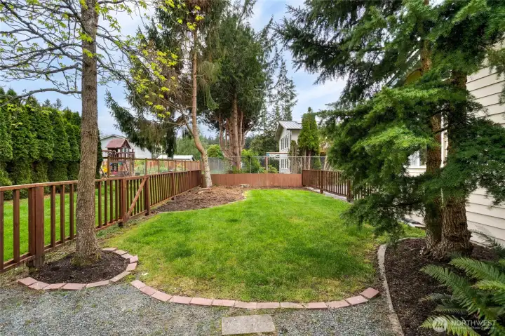Fenced backyard with a peaceful view toward the alleyway, where deer are often spotted grazing.
