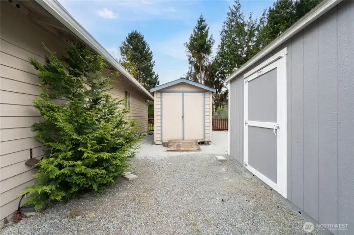 Two storage sheds on site—one featuring a window and shelving, the other equipped with a workbench.