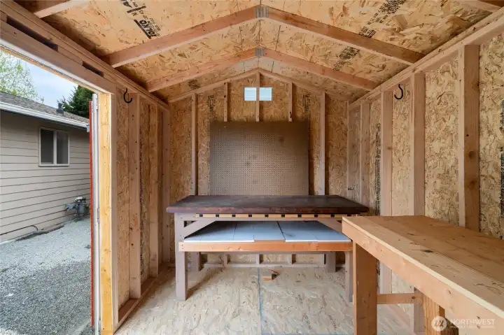 Tuff Shed with two workbenches and a pegboard for tools.