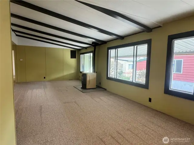 You can see it all here, the large open concept living room with vaulted ceilings with exposed rich dark beams. The pellet stove and wood wrapped windows.