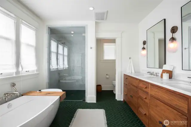 Primary bathroom with heated herringbone tile, walnut and marble double vanity, walk in shower, soaking tub and water closet.