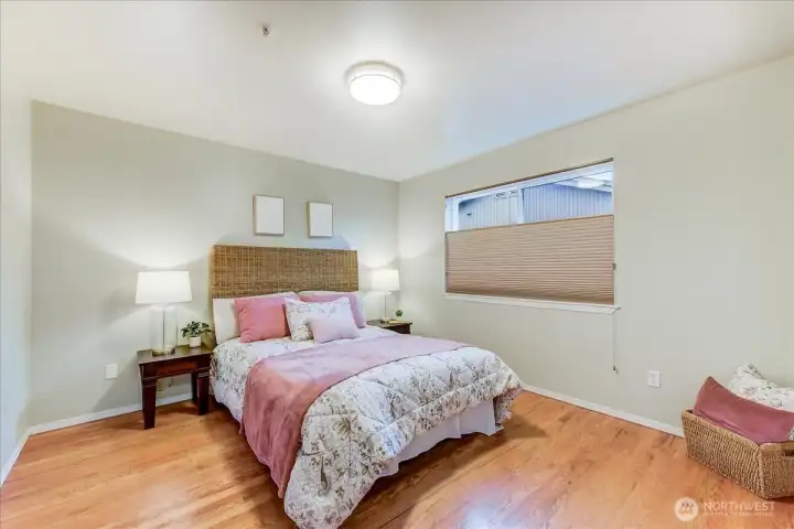 Primary suite with hardwood floors, a walk-in closet, and attached bath