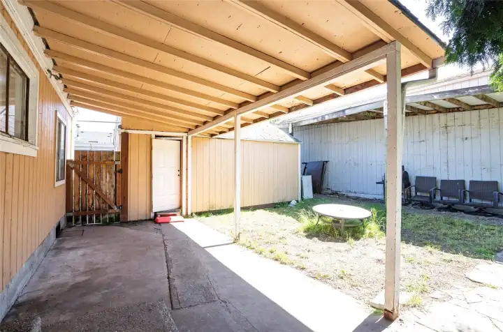 Another view of the covered patio with access to the detached single-car garage and the detached shop to the right.