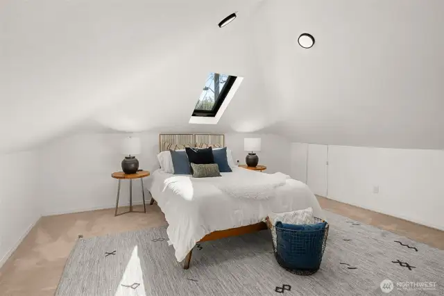 Spacious vaulted primary bedroom, features mini splits, skylight, and a custom closet fixtures.